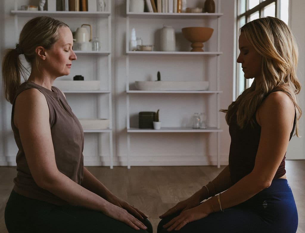 Two practitioners seated facing each other in quiet practice